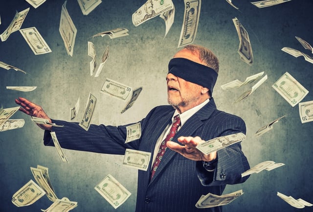 Blindfolded senior businessman trying to catch dollar bills banknotes flying in the air on gray wall background. Financial corporate success or crisis challenge concept  .jpeg