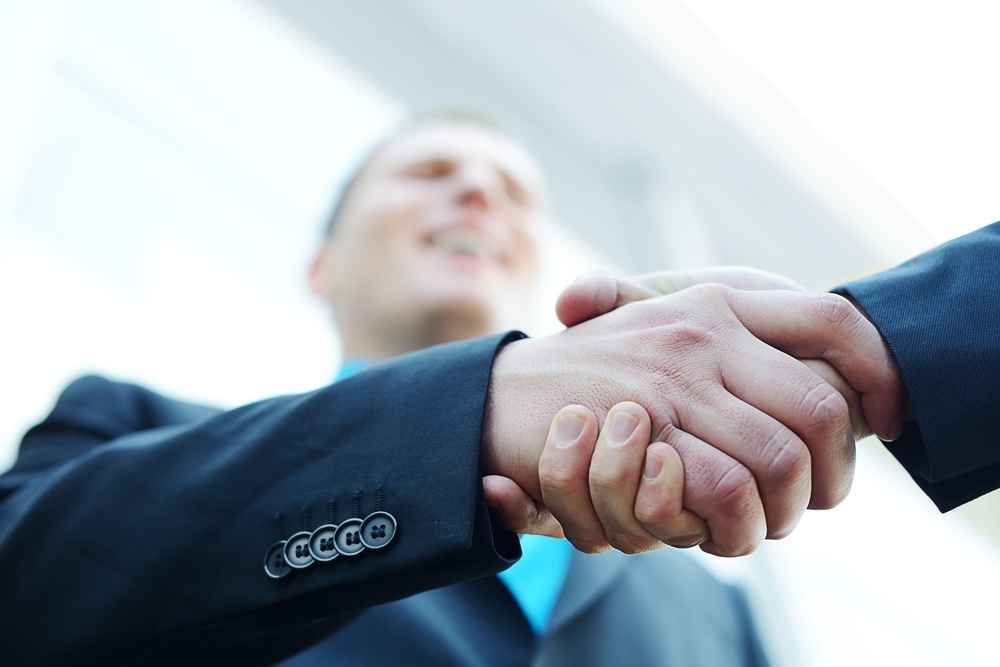 Business shaking hands in front of modern building with copy space (selective focus).jpeg