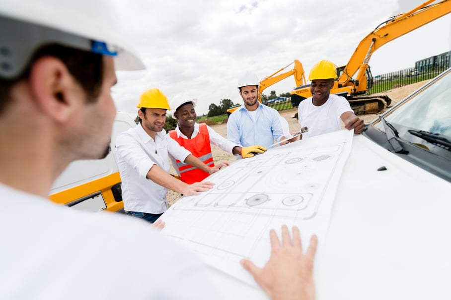 Group of architects looking at blueprints at a construction site